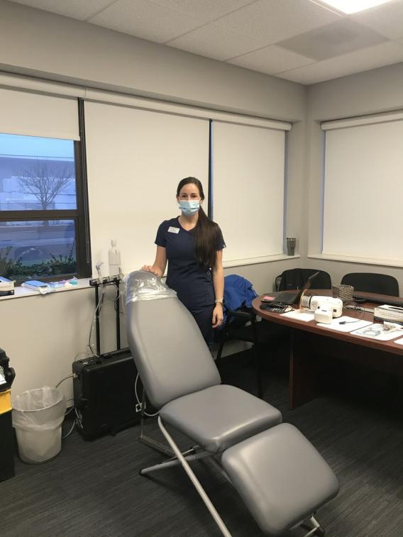 A member of the Advantage Dental Community Care Team posing next to a dental chair waiting for her next patient.